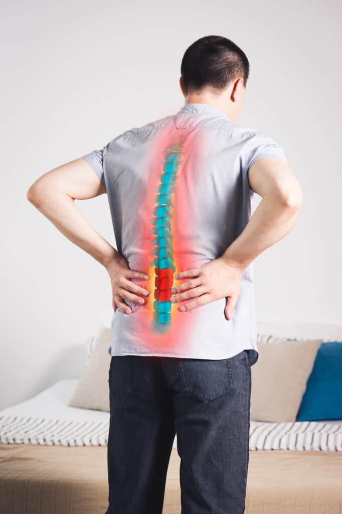 Pain in the spine, a man with backache at home, injury in the lower back, photo with highlighted skeleton