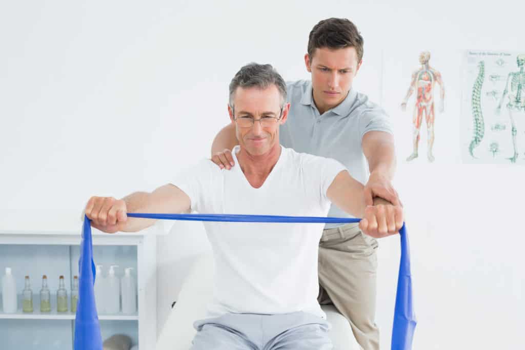 Man doing physical therapy exercise with doctor to help with shoulder pain