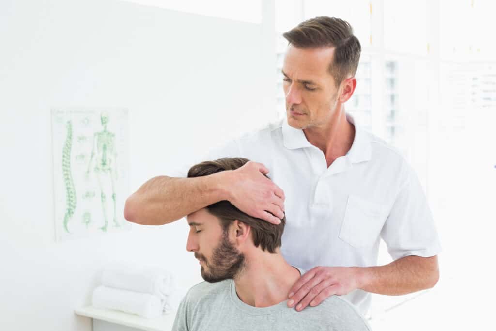 Male physical therapist doing neck adjustment in the medical office